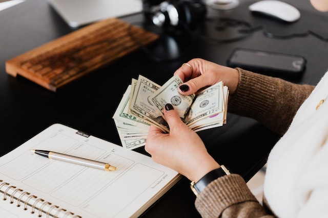 Person sitting at their desk counting dollar bills